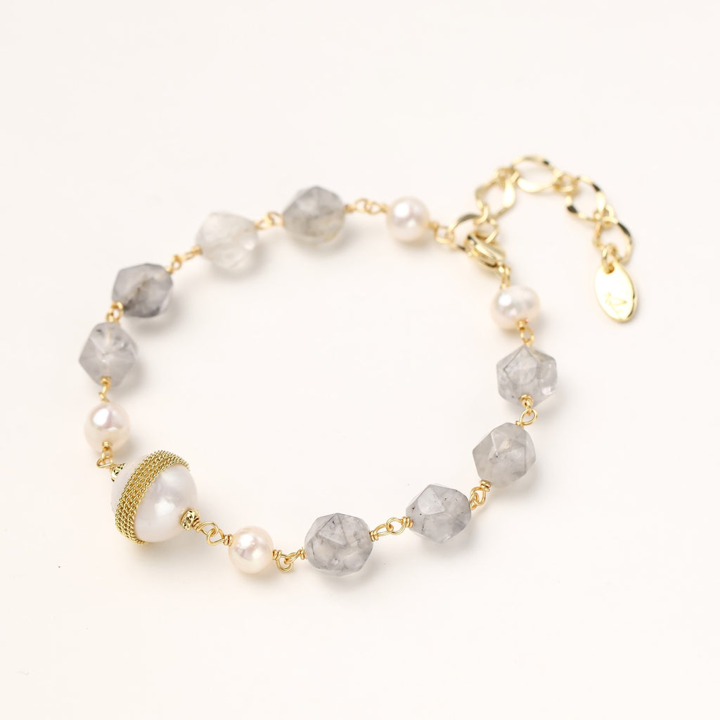 Gold-plated bracelet with white freshwater pearls and translucent grey crystals, featuring mesh-wrapped baroque pearl centerpiece