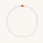 Stretch bracelet with white jade beads, freshwater pearls, and orange agate centerpiece on cream background.
