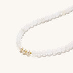 Stretch bracelet with white jade beads, freshwater pearls, and orange agate centerpiece on cream background.