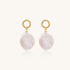 Gold-plated twisted stud earrings with large blush baroque pearls hanging elegantly on white background.
