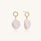 Gold-plated twisted stud earrings with large blush baroque pearls hanging elegantly on white background.