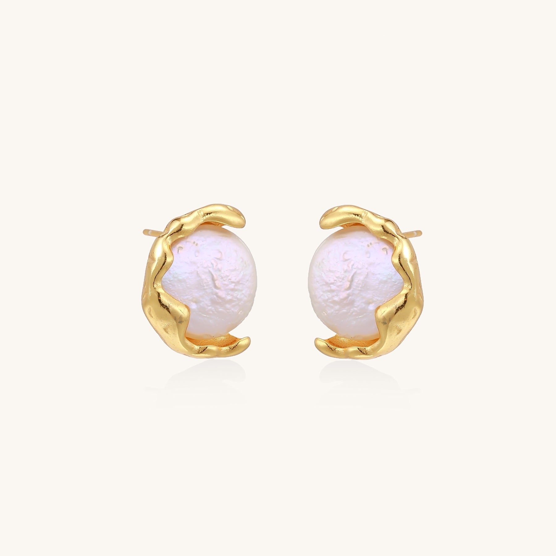 Gold-plated sterling silver stud earrings with organic claw settings cradling lustrous freshwater pearls on white background.