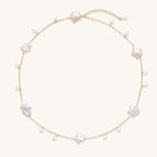 Delicate gold chain necklace with star-shaped baroque pearls and small freshwater pearls on cream background.
