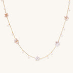 Delicate gold chain necklace with star-shaped baroque pearls and small freshwater pearls on cream background.