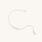 Delicate sterling silver chain bracelet with an organic white baroque pearl centerpiece on neutral background