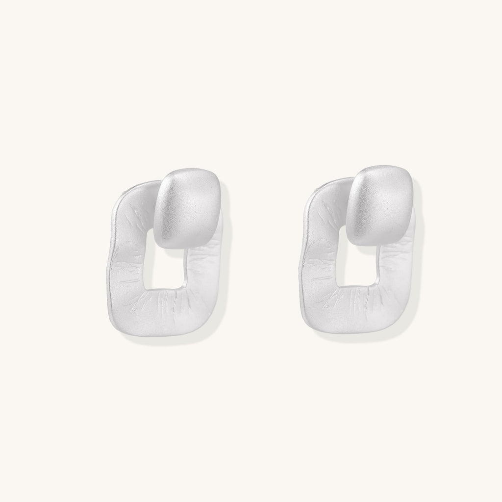 Geometric sterling silver square stud earrings with brushed texture and central square cutouts on white background.