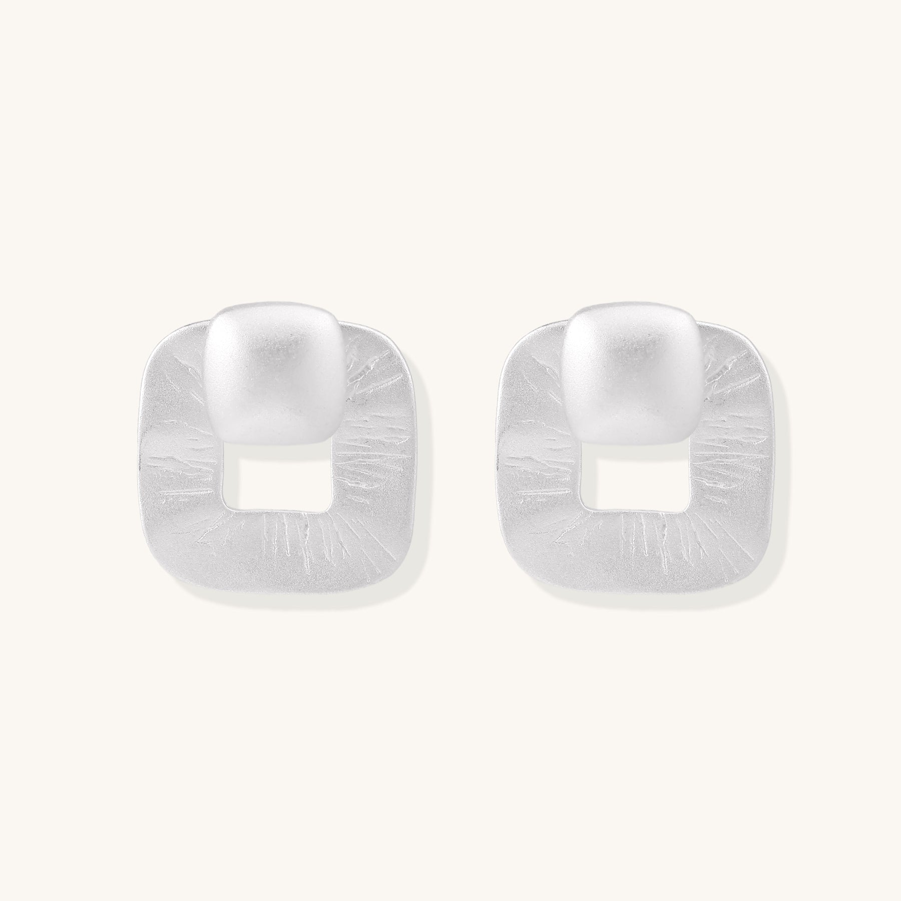Geometric sterling silver square stud earrings with brushed texture and central square cutouts on white background.