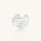 Wide sterling silver ring with flowing wave patterns and adjustable cuff design on white background.