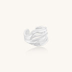 Wide sterling silver ring with flowing wave patterns and adjustable cuff design on white background.