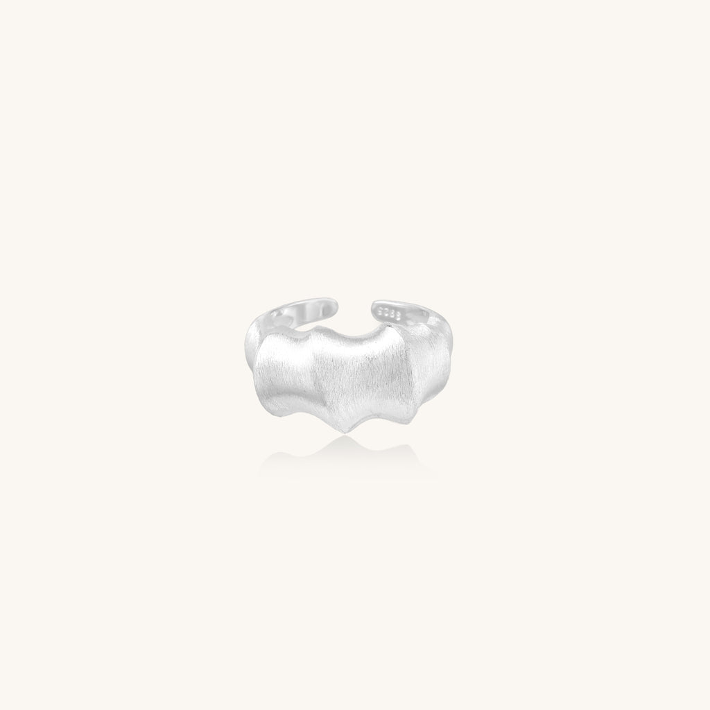 Chunky sterling silver ring with organic flowing design and brushed matte finish on neutral background
