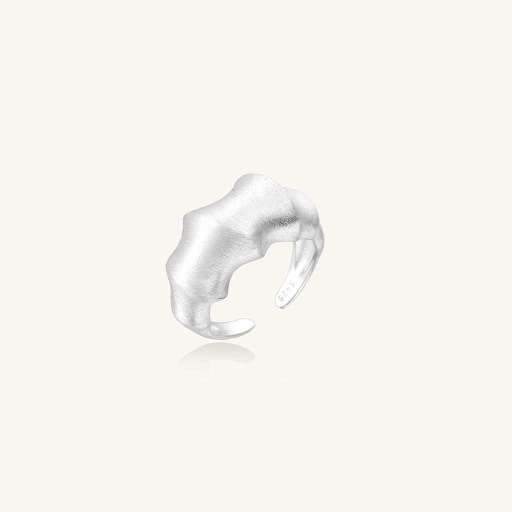 Chunky sterling silver ring with organic flowing design and brushed matte finish on neutral background