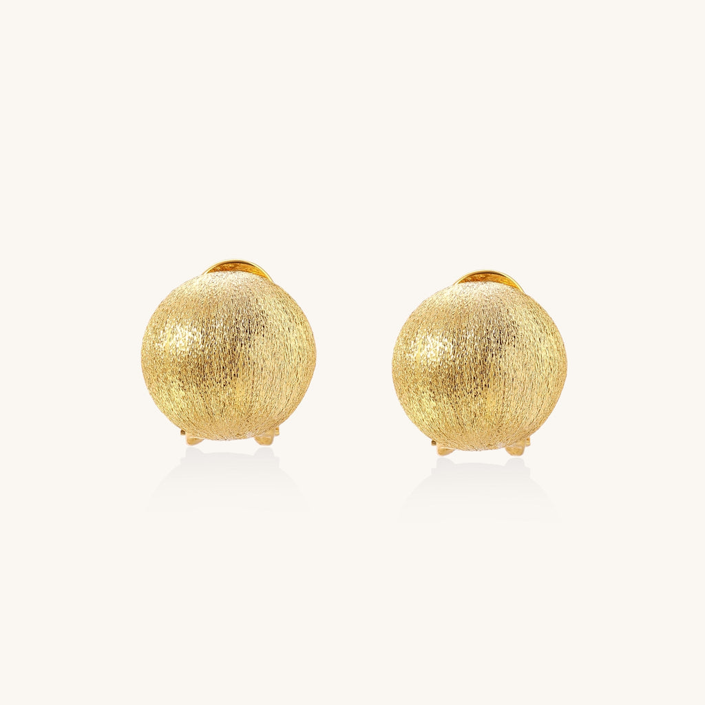 Close-up of textured gold-plated sterling silver dome clip-on earrings with brushed finish on white background.