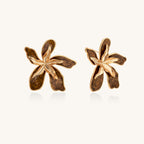 Large gold-plated flower earrings with brown enamel marbled petals on beige background, showing intricate floral design.