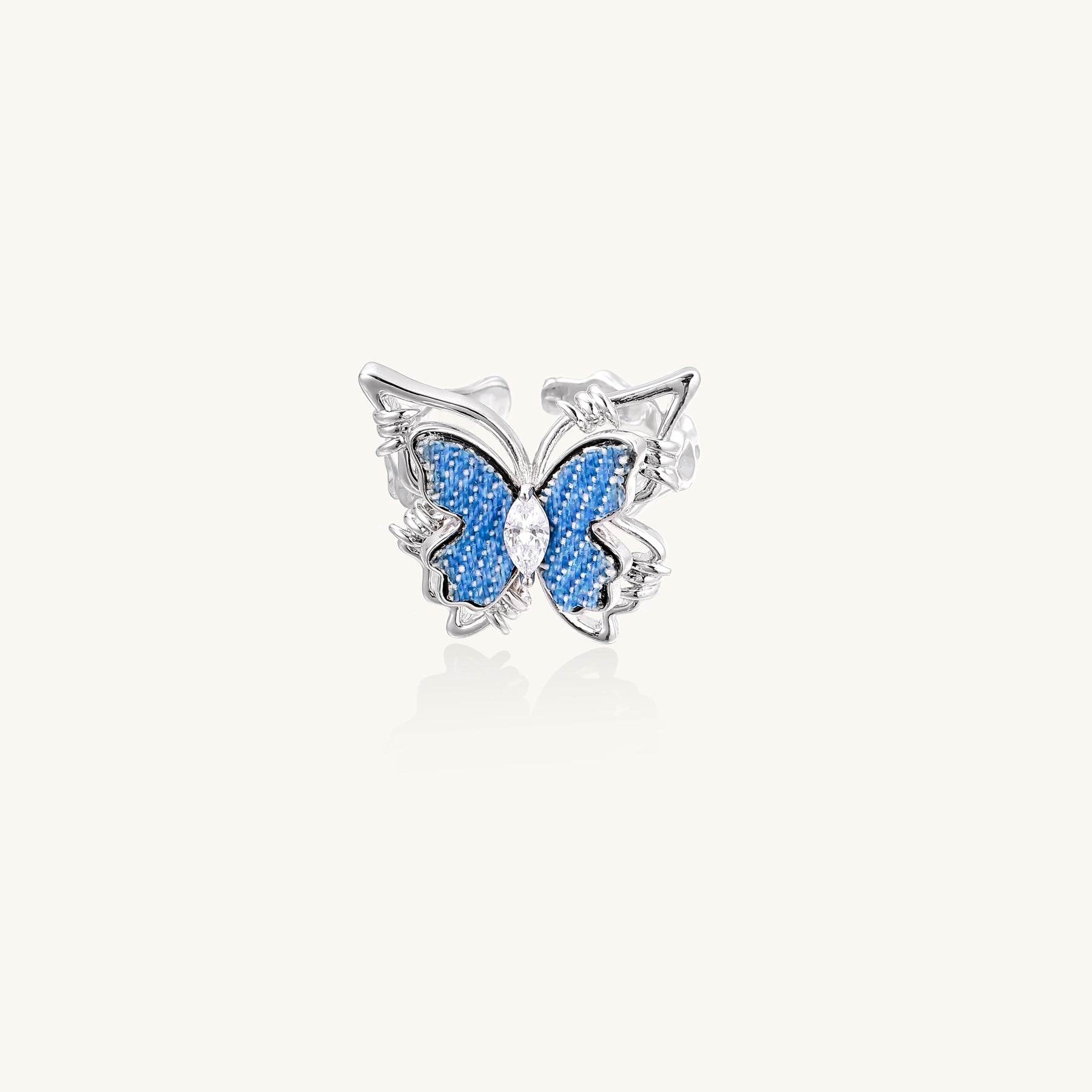 Gold-plated brass ring featuring blue butterfly design with central zirconia stone on neutral background.