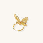 Adjustable gold-plated brass butterfly ring with intricate filigree cutout patterns and cubic zirconia accents on white background.