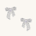 Gold and silver bow-shaped earrings with intricate lattice pattern and clear zirconia stones on neutral background.