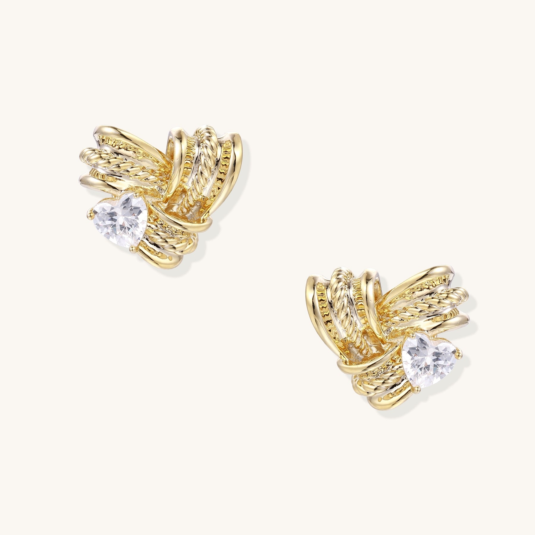 Close-up of gold-plated twisted rope design stud earrings with clear zirconia crystals on white background.