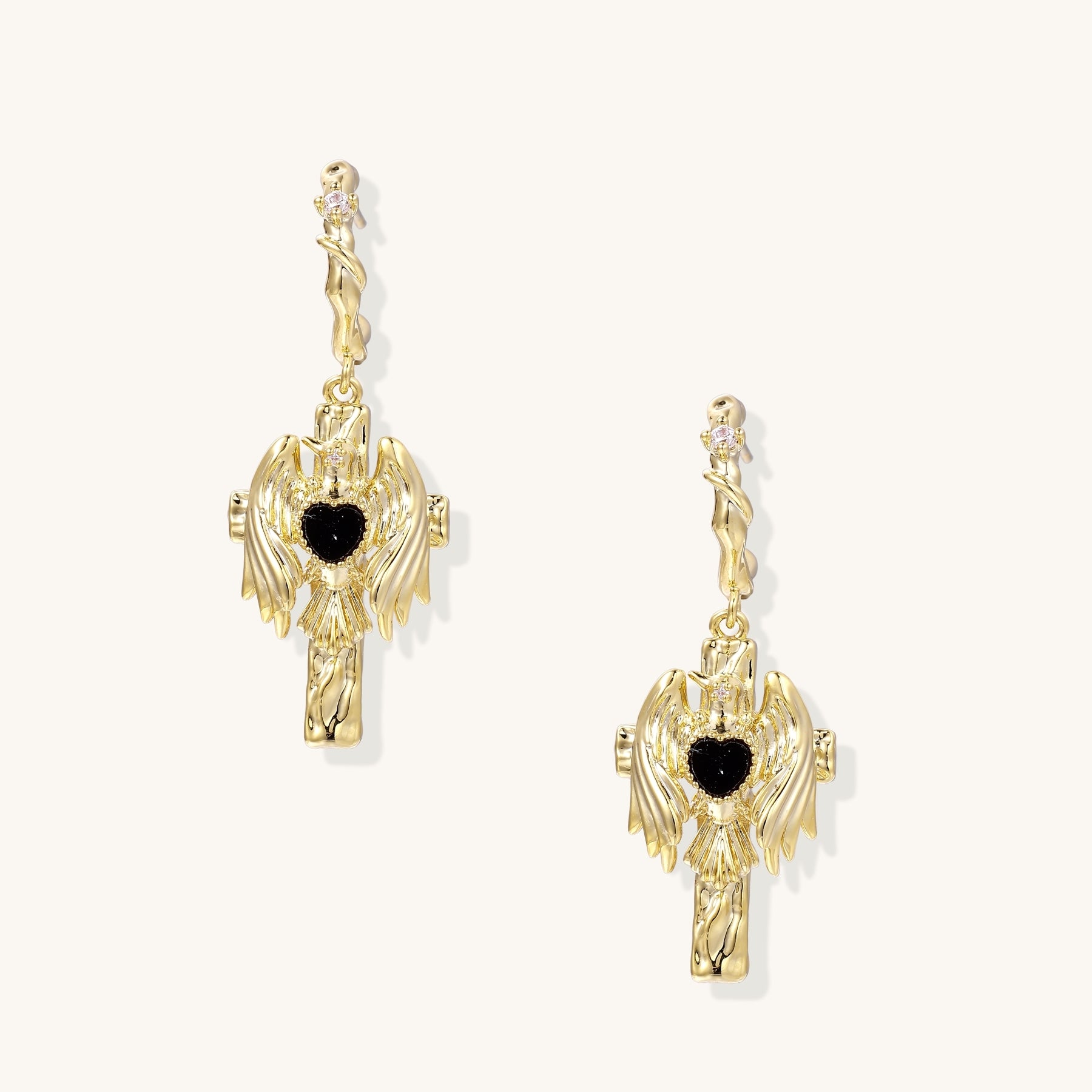 Ornate gold-plated drop earrings featuring wing designs with black zirconia heart centers on light background.