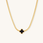 Delicate gold-plated chain necklace featuring a black quatrefoil clover pendant on white background.