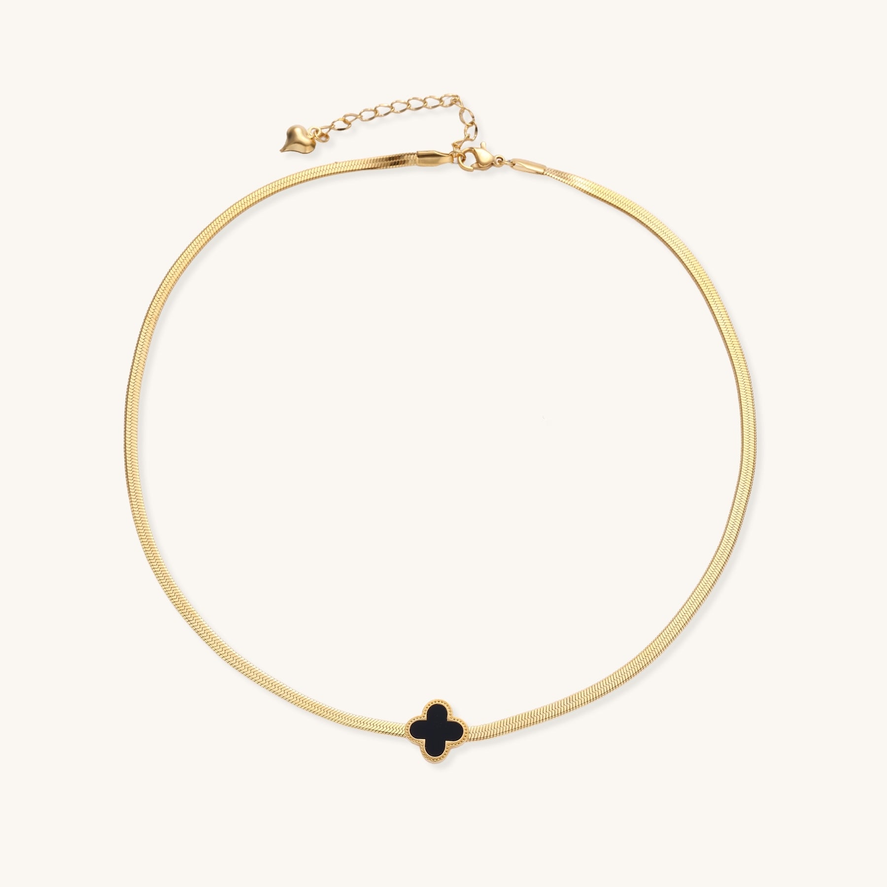 Delicate gold-plated chain necklace featuring a black quatrefoil clover pendant on white background.