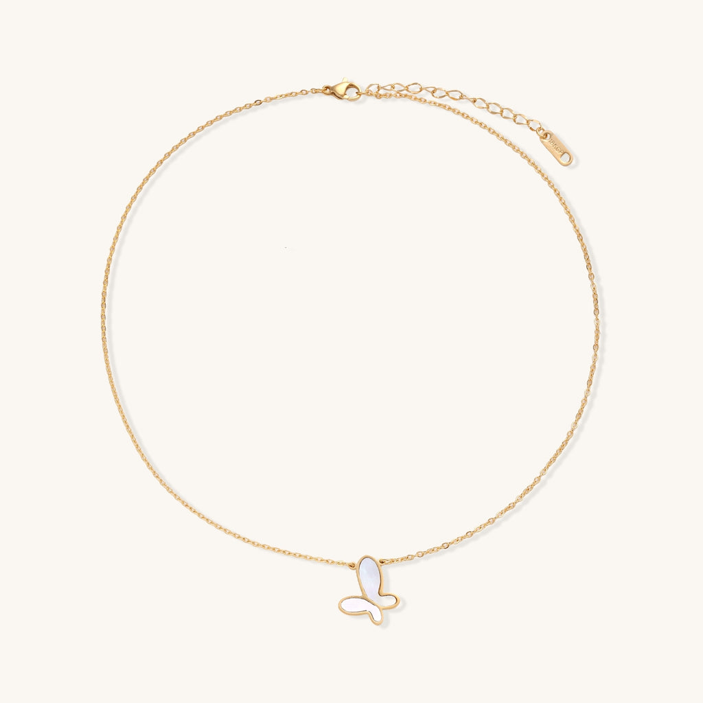 Delicate gold butterfly necklace with white mother of pearl wings on fine chain, displayed on neutral background.