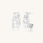 Textured gold-plated hoop earrings with flowing ripple design displayed on clean white background.