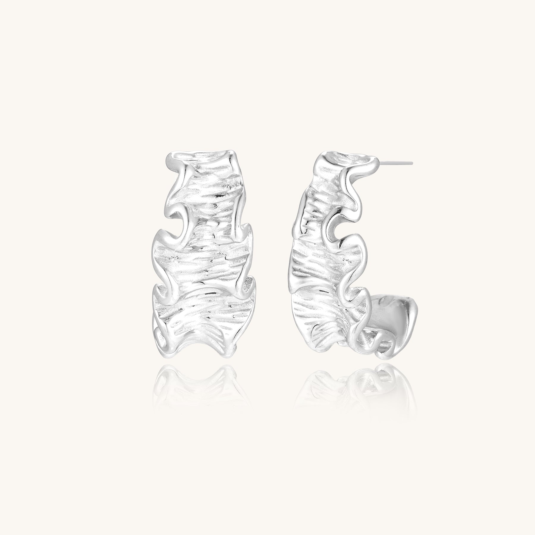 Textured gold-plated hoop earrings with flowing ripple design displayed on clean white background.