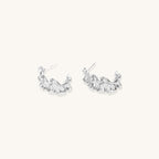 Textured gold-plated hoop earrings with flowing ripple design displayed on clean white background.