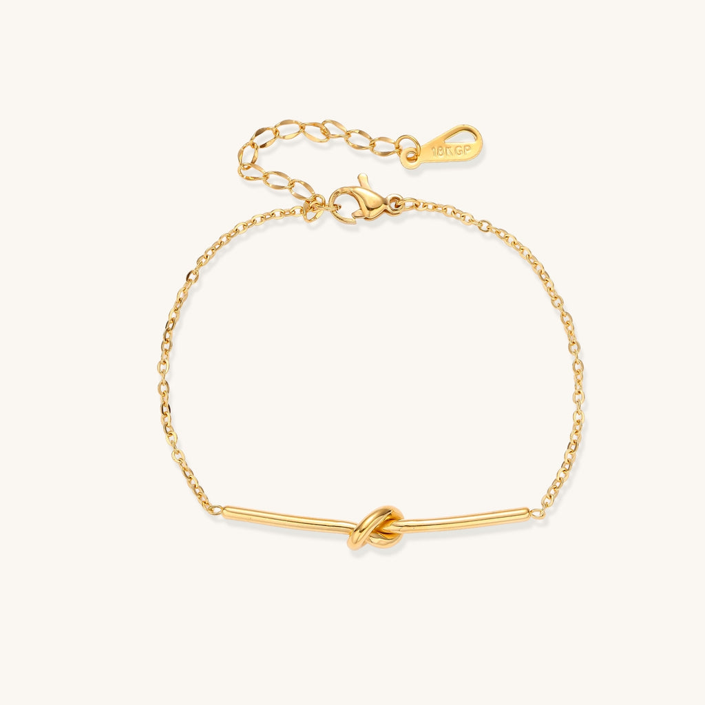 Delicate gold-plated chain bracelet with twisted knot bar detail and adjustable extender chain on white background.