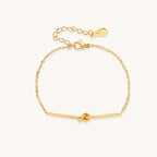 Delicate gold-plated chain bracelet with twisted knot bar detail and adjustable extender chain on white background.