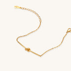 Delicate gold-plated chain bracelet with twisted knot bar detail and adjustable extender chain on white background.