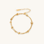 Delicate 18K gold plated bracelet with spherical beads on layered chains and adjustable extender on white background