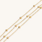 Delicate 18K gold plated bracelet with spherical beads on layered chains and adjustable extender on white background