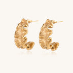 Textured gold-plated hoop earrings with wavy sculptural ridges displayed against a neutral background.