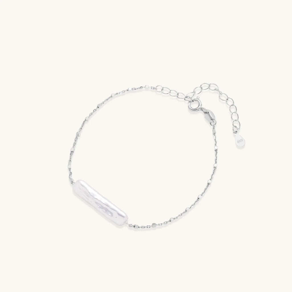 Minimalist bracelet with iridescent baroque pearl on rhodium-plated sterling silver chain against cream background