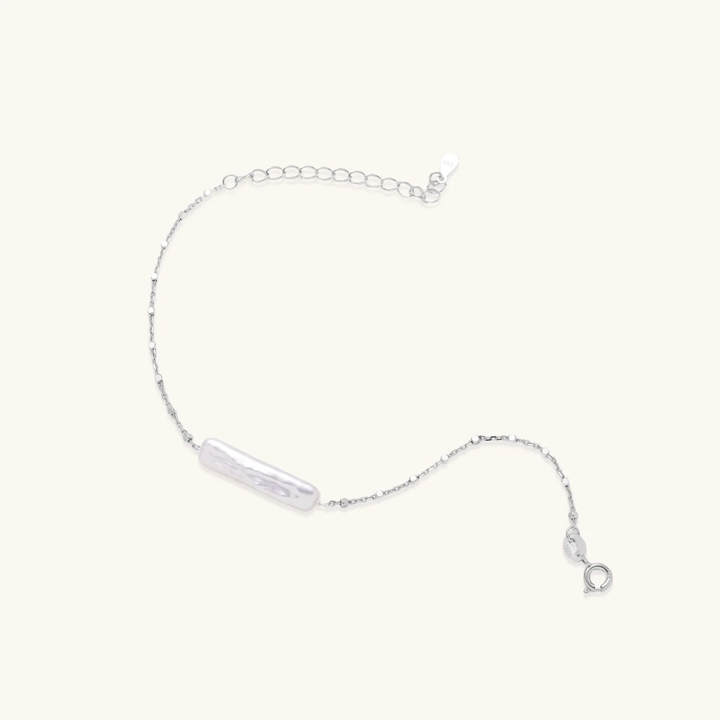 Minimalist bracelet with iridescent baroque pearl on rhodium-plated sterling silver chain against cream background