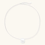 Minimalist brushed sterling silver dome pendant on delicate chain against cream background, showing matte textured finish